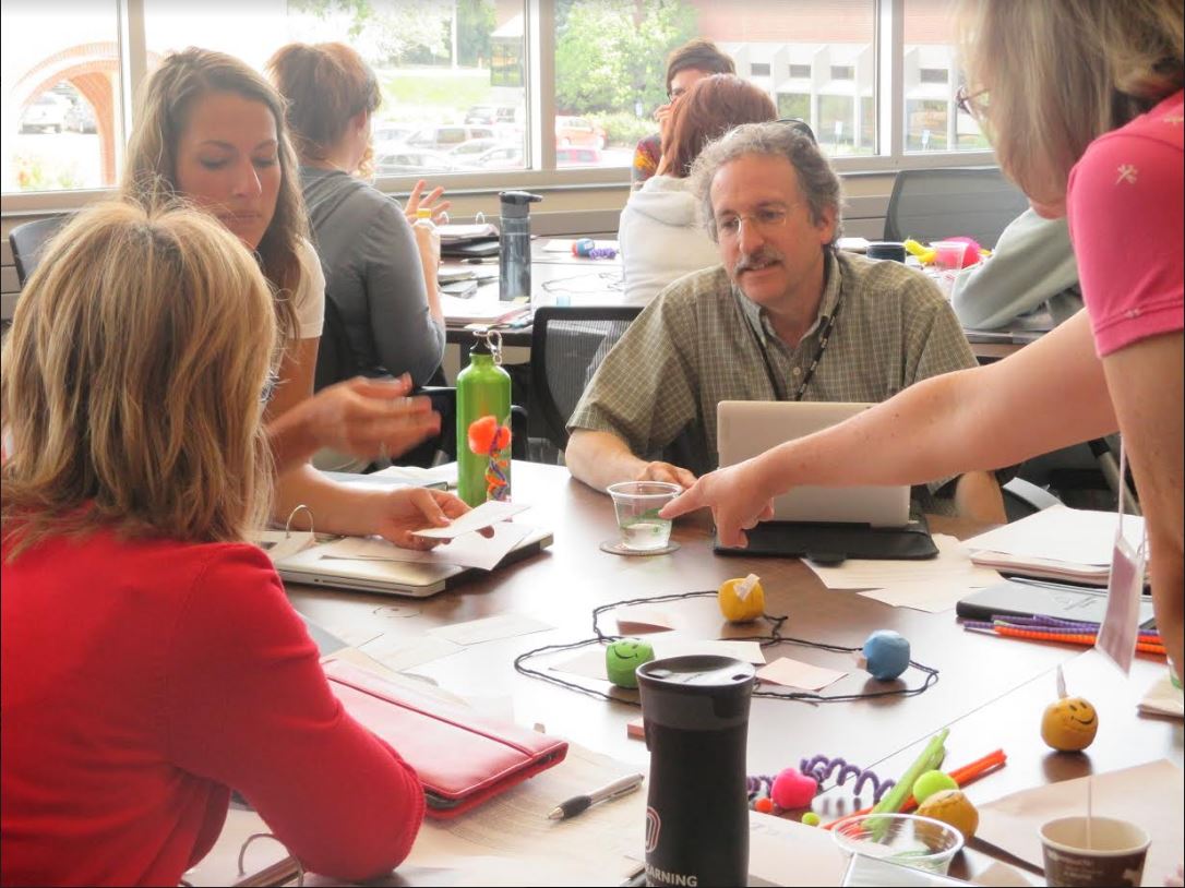 a group of people site together working at a table.